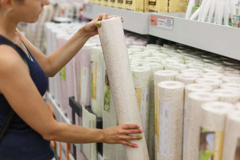 Femme choisissant un rouleau de papier peint dans un magasin